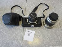Top and front view of Asahi Pentax Spotmatic F camera body, lens with cap attached, extra 28-80mm zoom lens, and black Pentax branded carrying case.