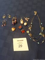 Top-down view of necklace and assorted earrings on black cloth