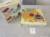 Two boxes of Fiesta Funday taco serving sets stacked beside one box of chip and dip serving set on a tiled table.