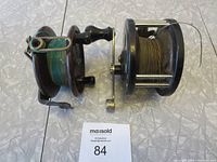 Top view of two vintage fishing reels side by side with fishing line on them.