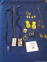 Full lot of fun costume jewelry laid out on blue fabric including various necklaces and earrings
