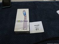 Photo showing Mobile Klean branded box with image of the UV sanitizing wand emitting blue light from the head of the device.
