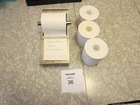 Photo showing silver Pottery Barn note dispenser alongside three extra paper rolls and a note with lot info.