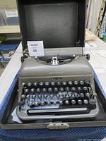 Front view of Remington Rand vintage typewriter showing gray body and keyboard layout with round black keys.
