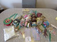 Wide shot showing an assortment of ribbons, beads, sequins, wire, and stickers on a table.