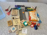 Overview of lots including various scissors, rubber stamps, a paper cutter, and paper punches spread on a table.