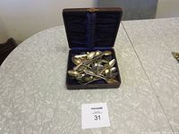 Wide view of the opened storage box containing multiple silver plated spoons on a table.