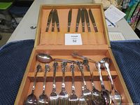 Full view of silverware set in box showing knives in the lid holder and forks, spoons, and serving spoons in the main section.