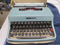 Front view of Olivetti Lettera 32 typewriter showing keyboard and body in light blue