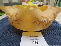 Side view of the vintage glass bowl showing raised blossoms and vine patterns with scalloped ruffled rim.
