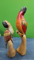 Two carved wood parrots standing side by side, showing full height and painted detail.