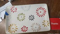 Top-down view of rectangular ceramic platter showing colorful flower burst pattern and glossy finish