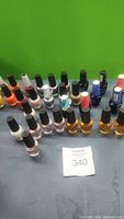 Photo showing 30 unopened OPI nail polish bottles arranged in rows on a gray surface with green background.
