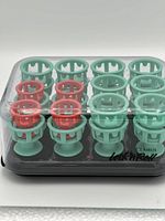 Set of 24 silicone curlers arranged on black heating base with metal rods visible.