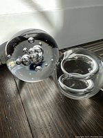 Both glass paperweights together showing the larger paperweight with multiple internal bubbles and the smaller with double ring design inside