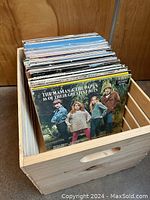 Wooden crate with a collection of assorted vinyl records, front record is The Mamas & The Papas '16 of Their Greatest Hits' album.