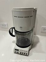 Front view of the Braun coffee maker showing digital display and carafe with measurement markings.