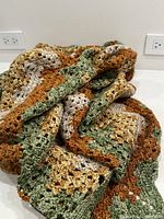 Close-up photo showing the crochet stitch pattern and color palette of the throw with folded view.