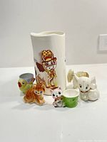 Group shot of all ceramic items including the cow jug and animal figurines mostly made in Japan.