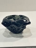 Dark black with green undertone sculptural glass bowl with flowing edges, shown from angled top to highlight form and color