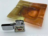 Close-up of amber and brown square glass ashtray with inset segmented design and light wear.