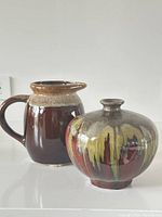 Broader view showing both glazed ceramic jug and rounded vessel, highlighting shapes and glazes