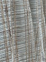 Close-up view of woven texture and vertical stripes in beige, cream, neutral fibers, and subtle grey accents.