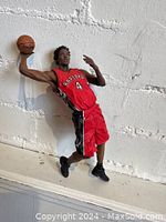 Front view of Chris Bosh action figure in Raptors uniform holding a basketball poised to dunk, showing detailed facial features and red/black uniform.