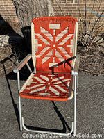 Front view of the vintage folding macrame lawn chair showing aluminum frame, armrests, and weaving detail.