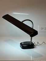 Side view of the black vintage desk lamp with rectangular lamp head and black base, showing white on/off button and original power cord.