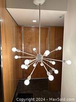 Full view of the lit chandelier from below showing all 16 arms and bulbs