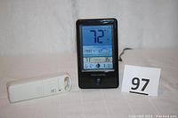 AcuRite digital weather forecaster with outdoor sensor shown side by side on white background. Forecaster displays 72°F outdoor temperature and weather forecast icon.