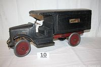 Side view of steel moving van toy showing cab, cargo box, wheels