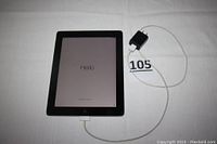 Front view of the black Apple iPad 2 tablet powered on showing 'Hello' screen with charging cord and wall adapter