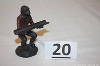 Front view of the cast iron monkey figurine holding the pen holder slot, showing details of posture and attire.