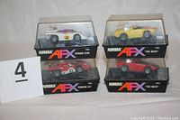 Four slot cars in original Aurora AFX plastic boxes, two stacked above two