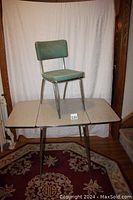 Table with drop leaves extended, chair placed on top to show scale and design.