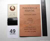 Photo of lot including Nixon signed brochure, bronze coin with display stand, and ruler for size reference.