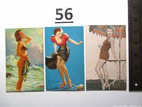 Photo of all three vintage mutoscope cards side by side with ruler for scale, showing the front illustrations and condition.