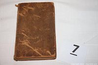 Closed view of the brown leather hardback book showing wear and scuff marks on covers and spine.