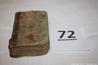 Antiquarian book showing front cover heavily worn and stained with leather spine.