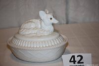 Full view of the milk glass covered candy dish displaying the fox figurine lid and basket-like textured base.