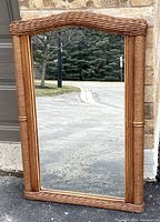 Front view of large rectangular mirror with bamboo and rattan cane frame showing arched top and woven cane detailing at sides and top.