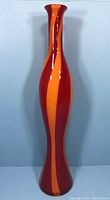 Front view of the tall vintage Murano vase with red and orange swirl pattern, showing the full height and flair.
