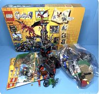 Overview of the LEGO Castle 70403 set including box, instruction manuals, and loose and bagged pieces with a dragon figure and cart visible.