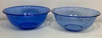 Two light blue Pyrex glass mixing bowls side by side showing color variation and size difference.