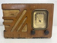 Front view of vintage wooden Philco tube radio showing decorative speaker grille and analog tuning dial with two knobs below.