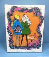 Front view of the vintage 1968 Barbie Doll Trunk Case showing the illustrated cover with two dolls and floral decorations.