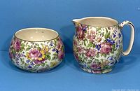 Front view of creamer and sugar bowl displaying floral pattern on white ceramic background