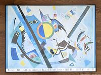 Full view of the framed lithograph print showing the artwork with blue and yellow abstract shapes, framed in black with a light blue matte.